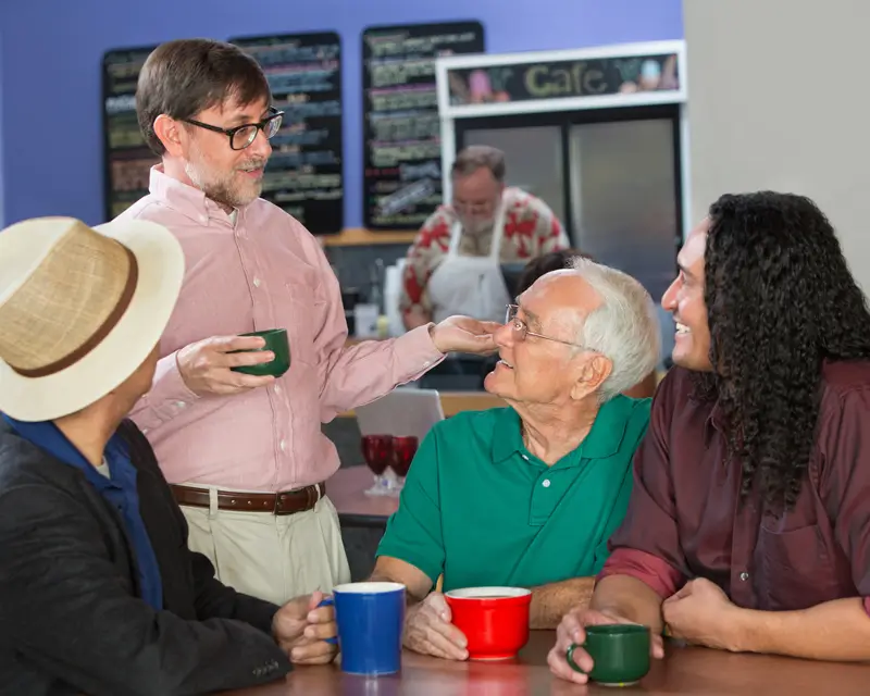 Man in glasses talking to a group of men of different ages at a community gather place